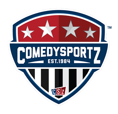 Large logo in the shape of a shield with a red top with white stars, black and white stripes at the bottom, and a blue stripe across the middle that says Comedy Sportz Established 1984